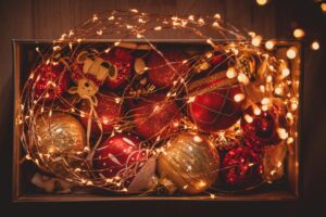 A box of vibrant Christmas ornaments wrapped in warm twinkling lights, perfect for holiday celebrations.